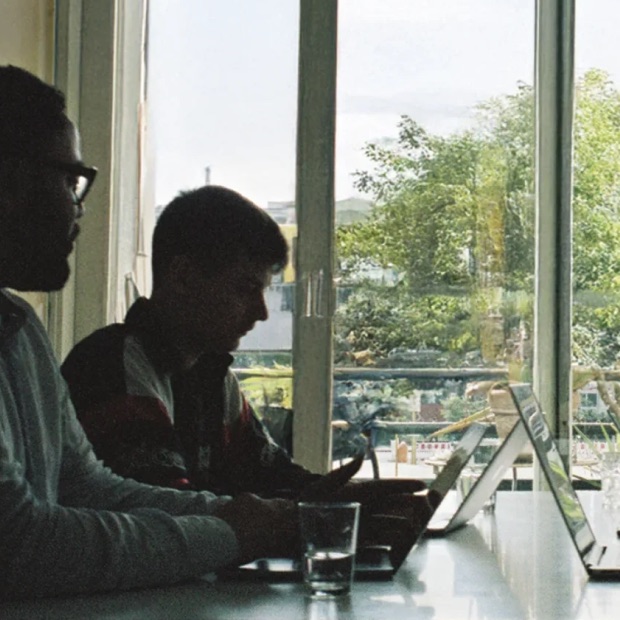 Zwei Kollegen analysieren am Fenster Kundendaten am Laptop